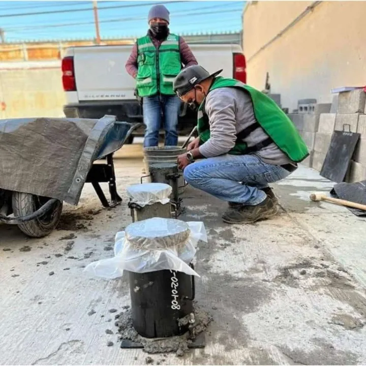 Técnicos de Layen con chaleco verde muestreando concreto en moldes de cilindro en obra