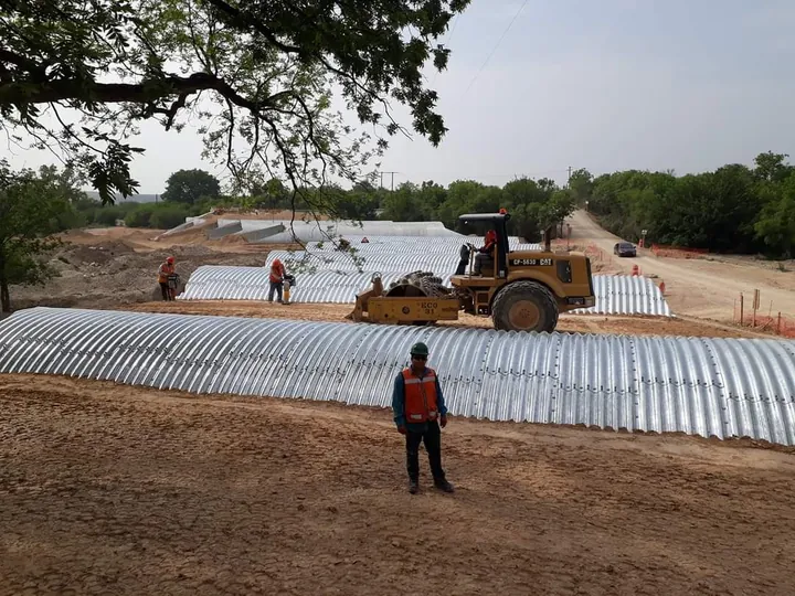 Obra de drenaje con alcantarilla de lámina corrugada y rodillo compactador