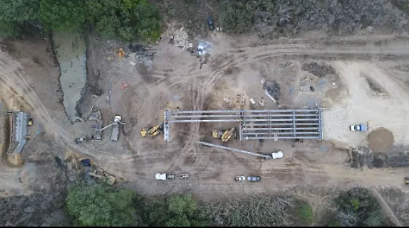 Toma aérea de una obra de puente con terracerías y maquinaria